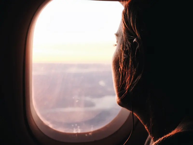 Viajero mirando por la ventanilla del avión al atardecer